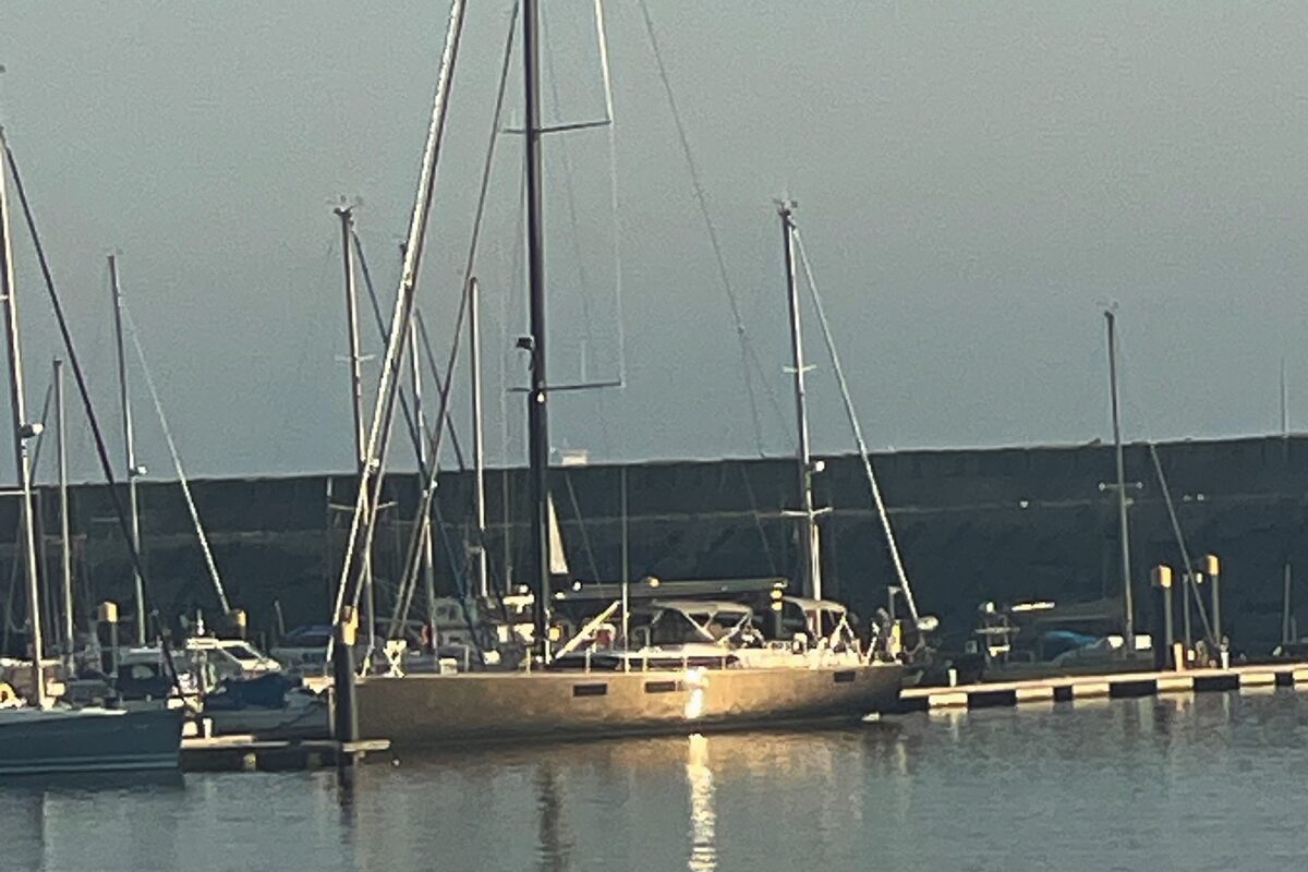 Grey hulled yacht moored up along side a pontoon beside a harbour wall
