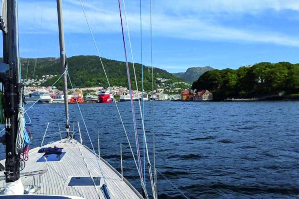 View from a wooden slatted foredeck of a sailing boat looking towards the shore